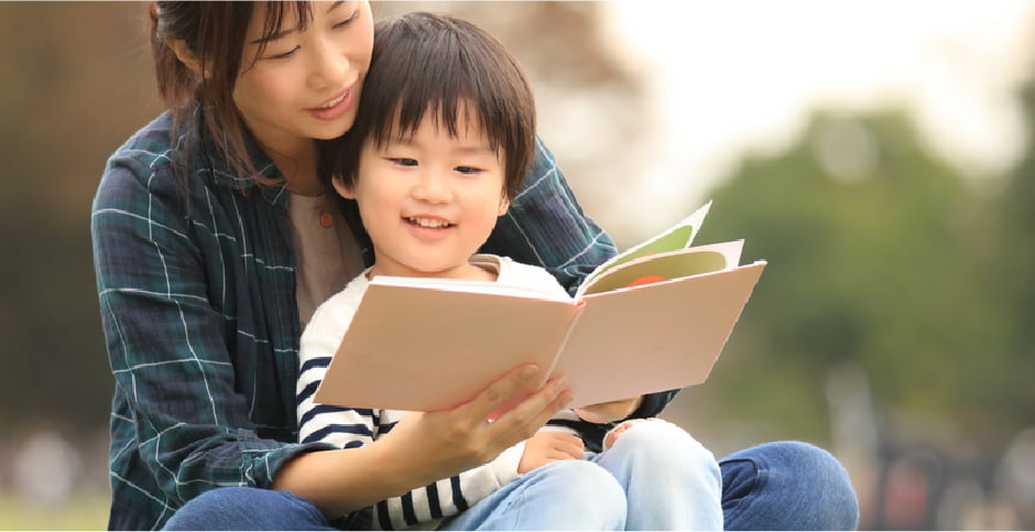 調査のイメージ写真：母親が子どもをだっこして絵本を読んでいる様子